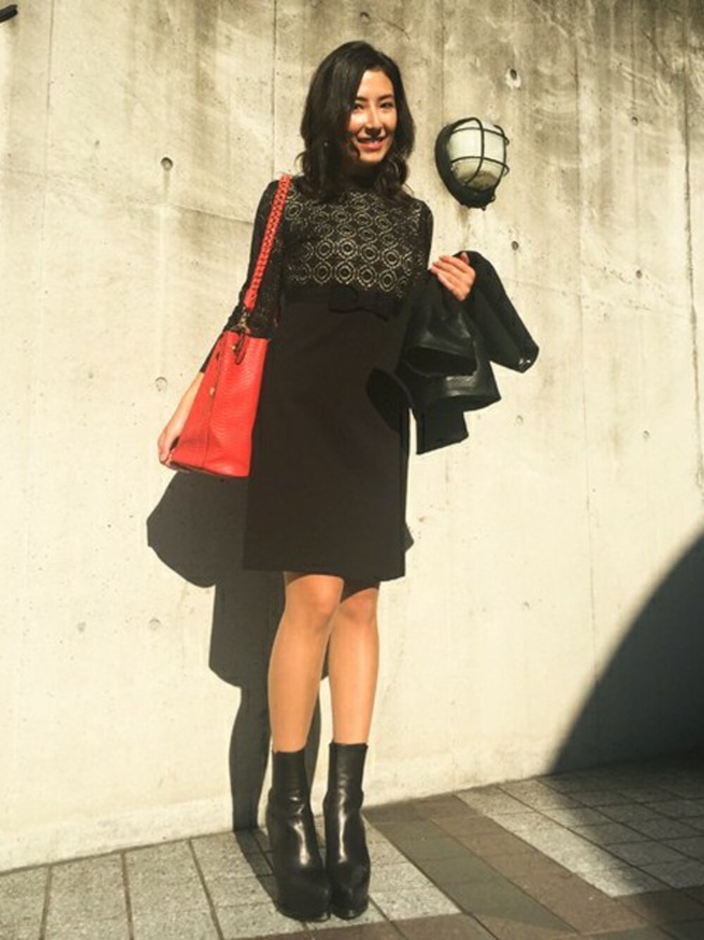 ブラック系のワンピース、レッド系のショルダーバッグを着用したレディースの秋コーディネートの1枚目の写真