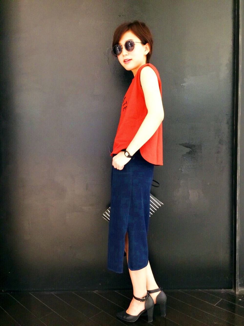 ブルー系のスカート、レッド系のタンクトップ、ブルー系のクラッチバッグを着用したレディースの夏コーディネートの1枚目の写真