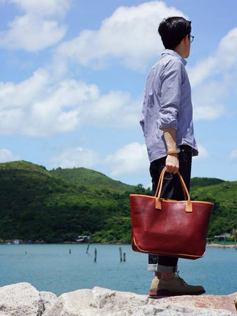 ブラウン系のトートバッグ、ブルー系のシャツ/ブラウス、ブルー系のデニムパンツを着用したメンズの夏コーディネートの1枚目の写真