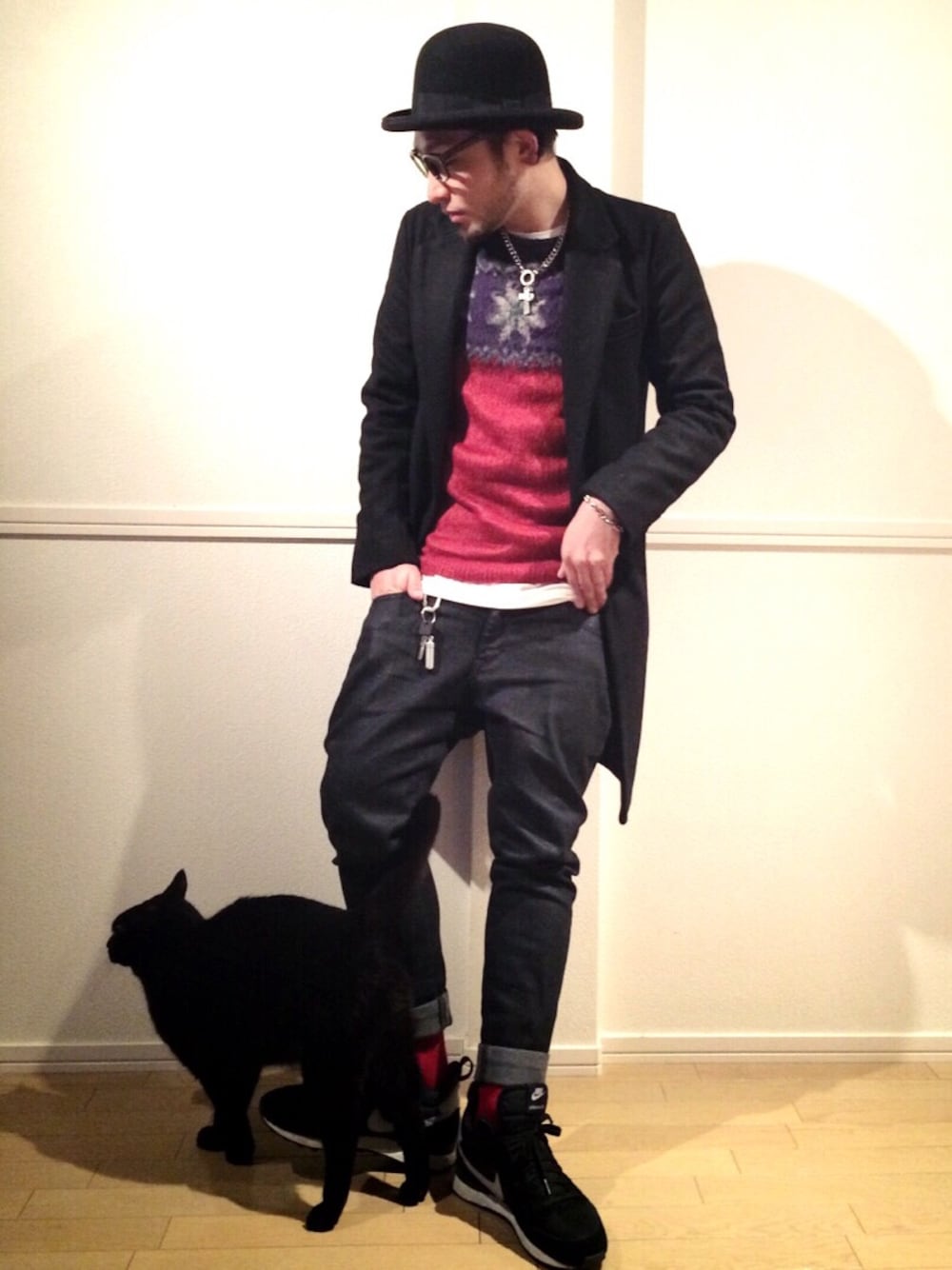 ブラック系のその他パンツ、レッド系のニット/セーター、ブラック系のチェスターコートを着用したメンズの冬コーディネートの1枚目の写真