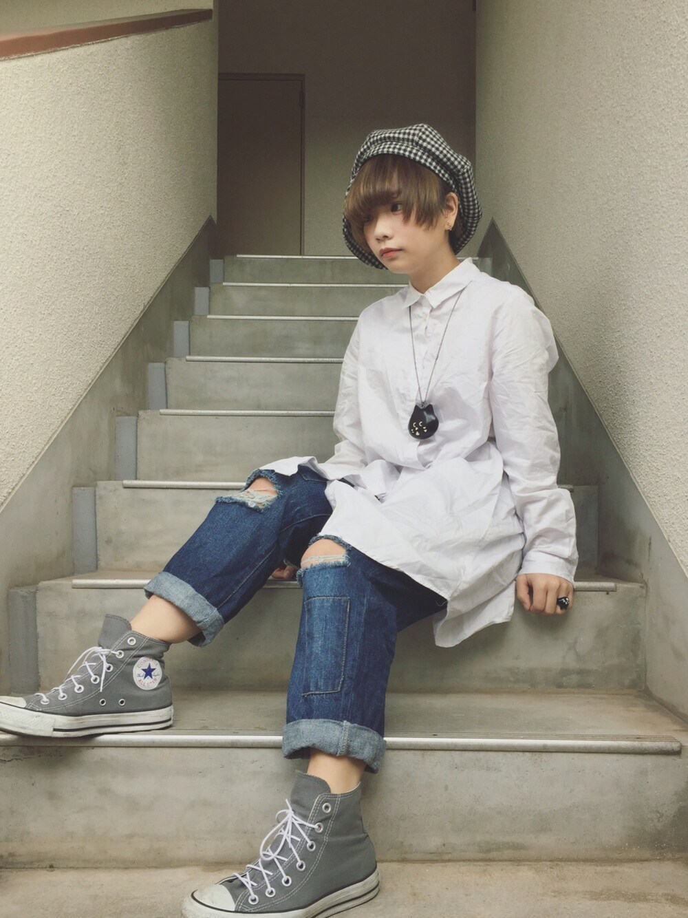 ホワイト系のシャツワンピース、ブルー系のデニムパンツ、グレー系のスニーカーを着用したレディースの春コーディネートの1枚目の写真