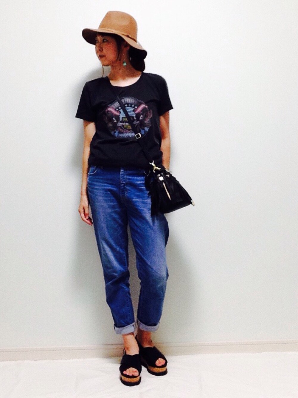 ブルー系のデニムパンツ、ブラック系のTシャツ/カットソー、ブラック系のショルダーバッグを着用したレディースの夏コーディネートの1枚目の写真