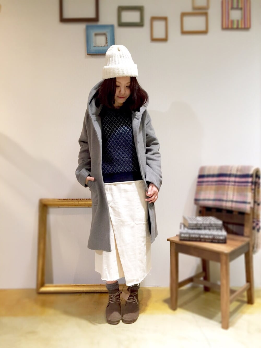 ベージュ系のスカート、グレー系のジャケット/アウター、ブルー系のニット/セーターを着用したレディースの冬コーディネートの1枚目の写真