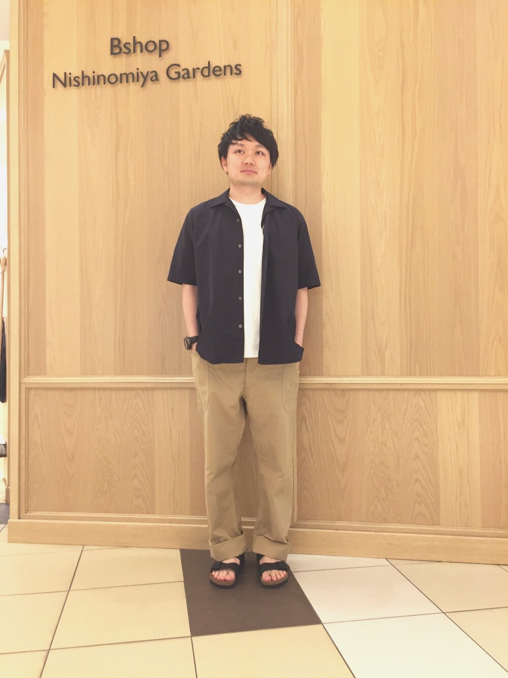 「COMOLI、Scye、ビルケンシュトック、半袖シャツ、白Tシャツ、リラックススタイル、サンダル、ワイドパンツ、Bshop」｜「COMOLIの【COMOLI(コモリ)】タイプライターオープンカラーシャツ（シャツ/ブラウス、ブルー系）」を使った、櫻井さん（メンズ・169cm）の春コーディネートの1枚目の写真