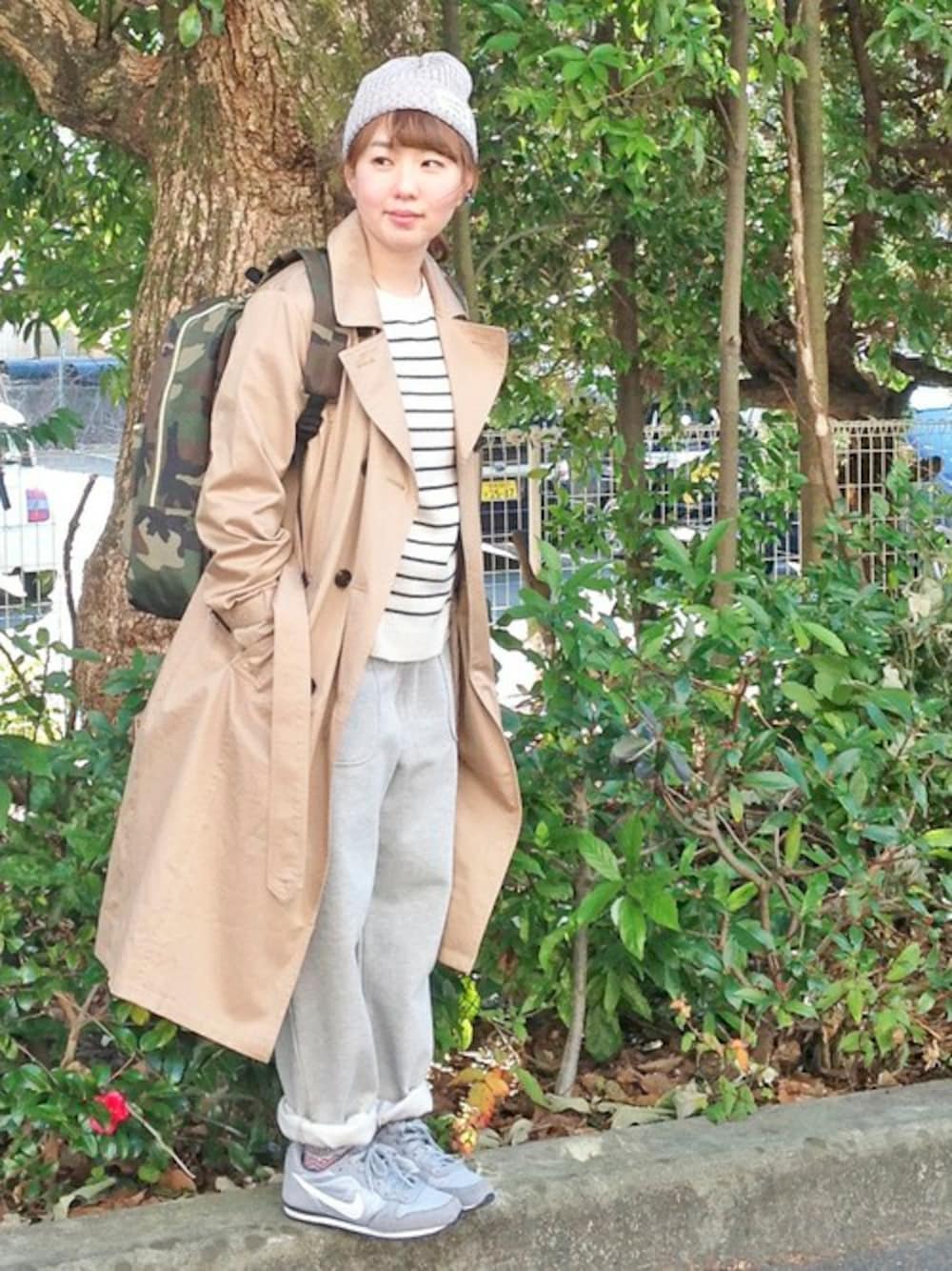 ベージュ系のトレンチコート、グレー系のその他パンツ、ホワイト系のニット/セーターを着用したレディースの冬コーディネートの1枚目の写真