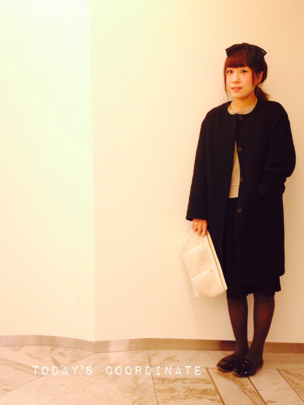 ブラック系のノーカラージャケット、ホワイト系のクラッチバッグを着用したレディースの冬コーディネートの1枚目の写真