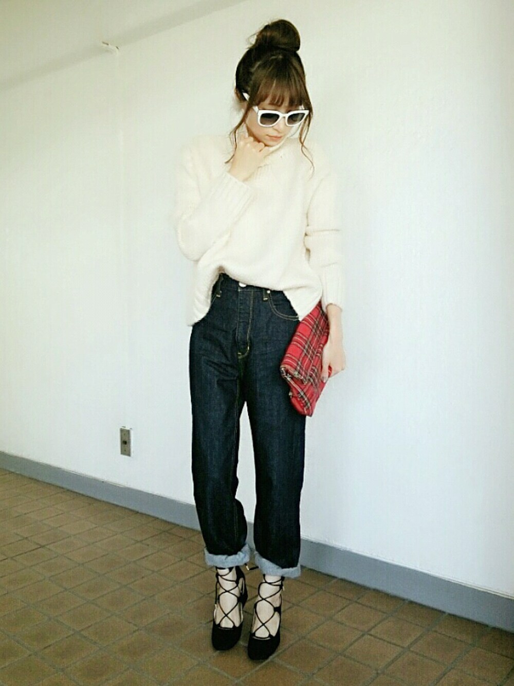 ブルー系のデニムパンツ、ブラック系のシューズ、レッド系のクラッチバッグを着用したレディースの秋コーディネートの1枚目の写真