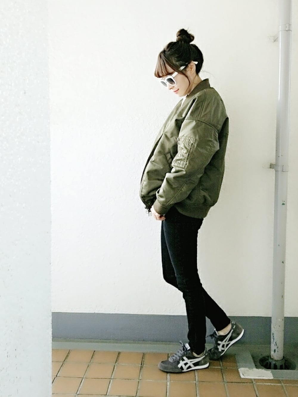 グリーン系のミリタリージャケット、ホワイト系のニット/セーター、ブラック系のデニムパンツを着用したレディースの冬コーディネートの1枚目の写真