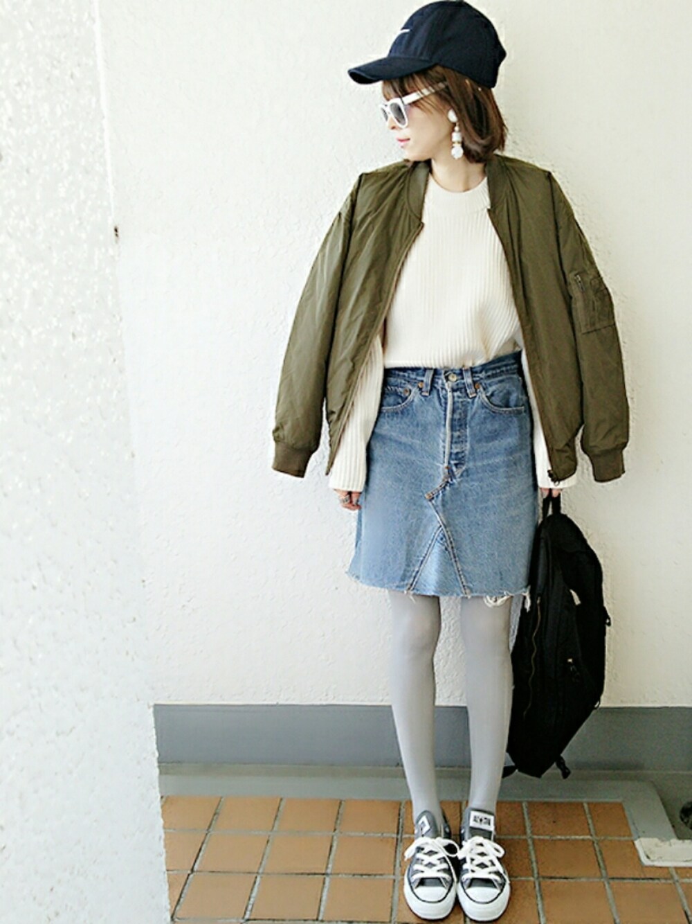 グリーン系のブルゾン、ホワイト系のニット/セーター、ブルー系のデニムスカートを着用したレディースの秋コーディネートの1枚目の写真