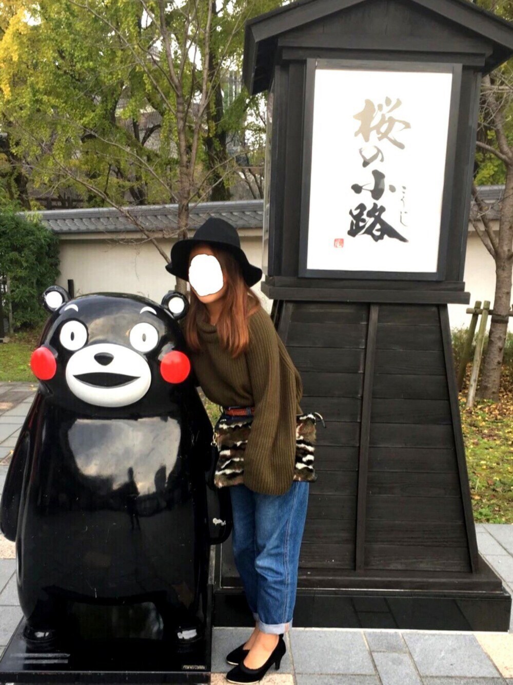 ブルー系のデニムパンツ、グリーン系のニット/セーター、グリーン系のクラッチバッグを着用したレディースの秋コーディネートの1枚目の写真