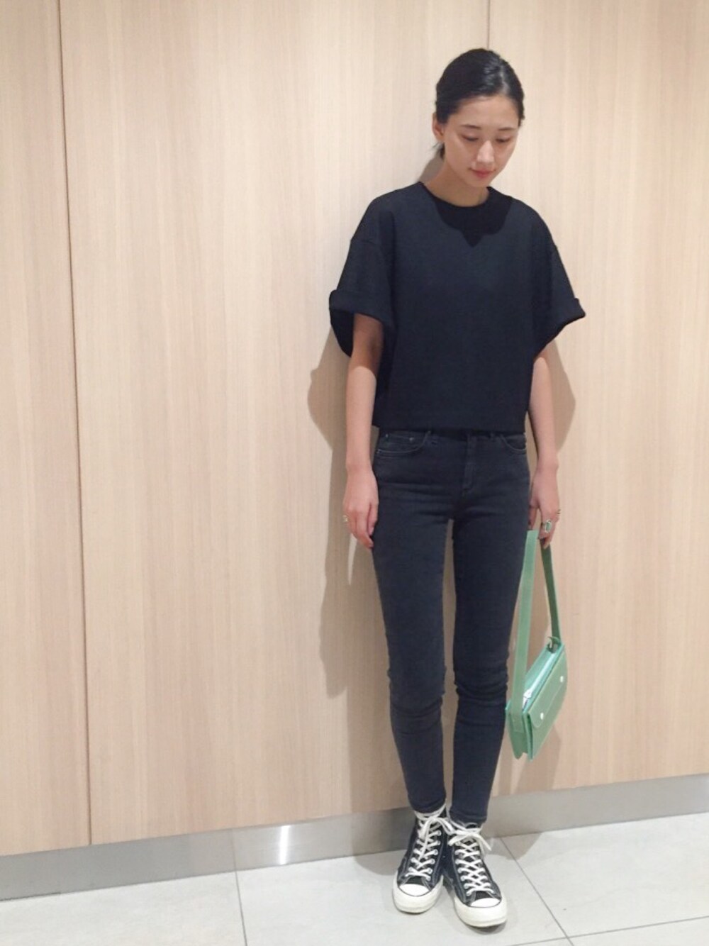 ブラック系のTシャツ/カットソー、ブラック系のデニムパンツ、グリーン系のバッグを着用したレディースの秋コーディネートの1枚目の写真