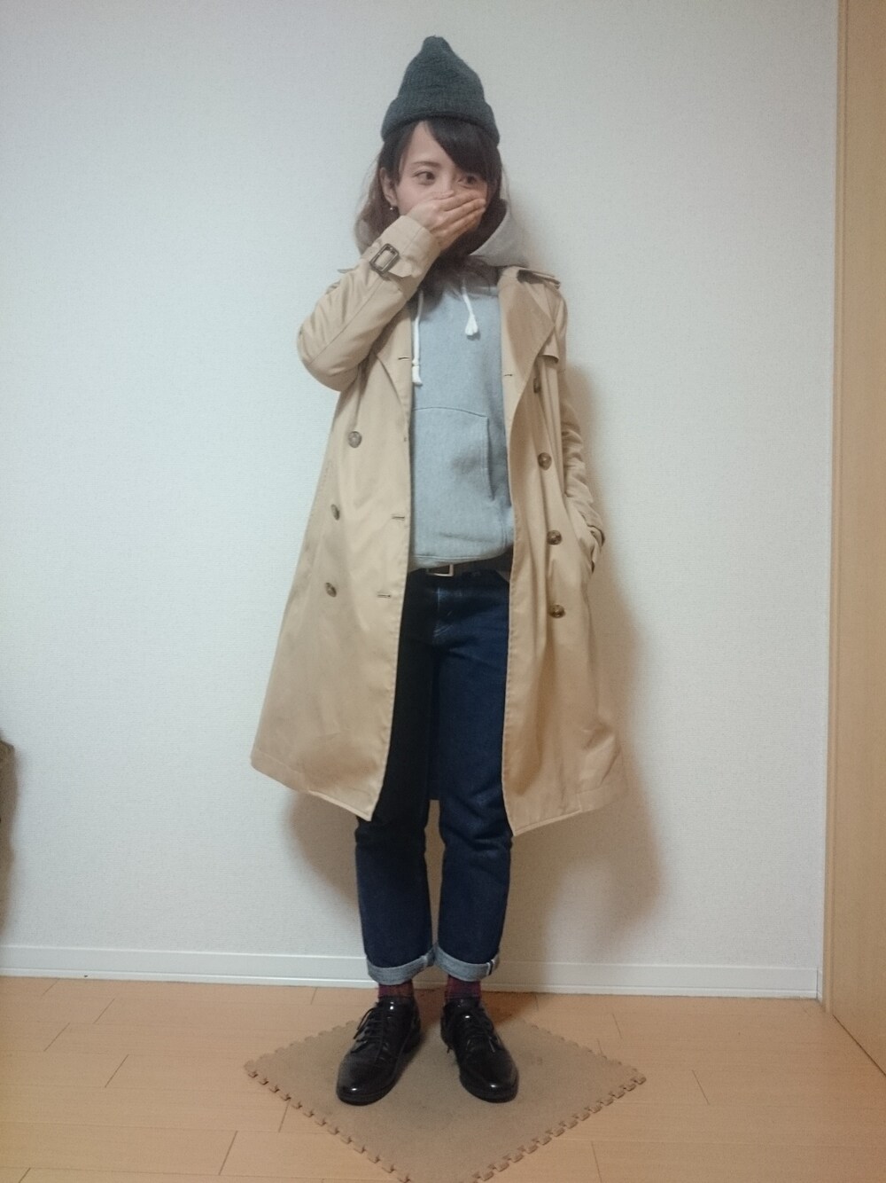ベージュ系のトレンチコート、グレー系のパーカー、ブルー系のデニムパンツを着用したレディースの秋コーディネートの1枚目の写真