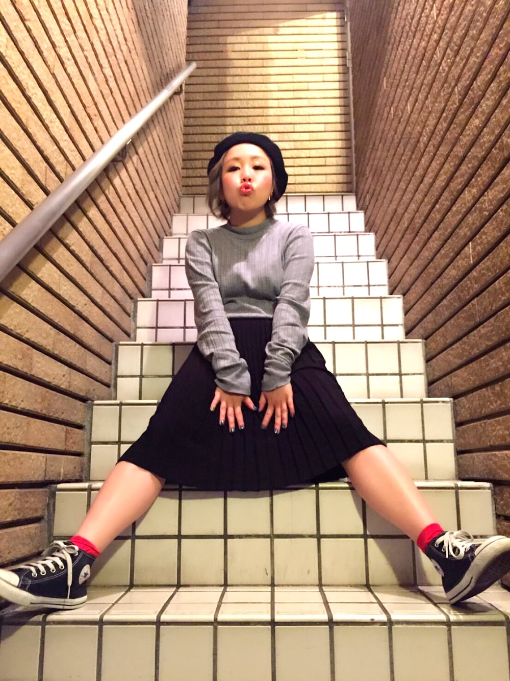 グレー系のニット/セーター、ブラック系のスカート、ブラック系のスニーカーを着用したレディースの秋コーディネートの1枚目の写真