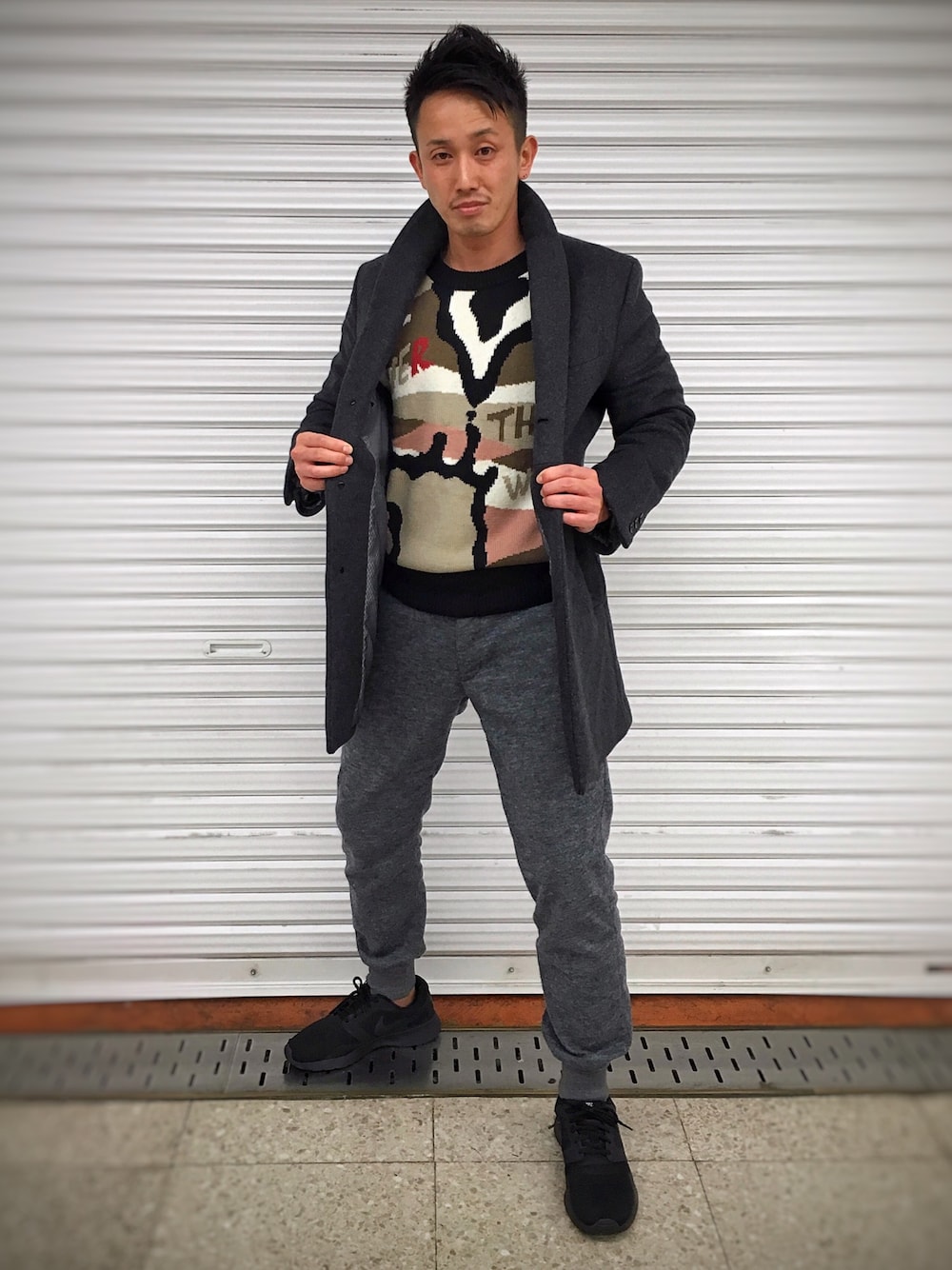 グレー系のピーコート、ブラック系のスニーカーを着用したメンズの冬コーディネートの1枚目の写真