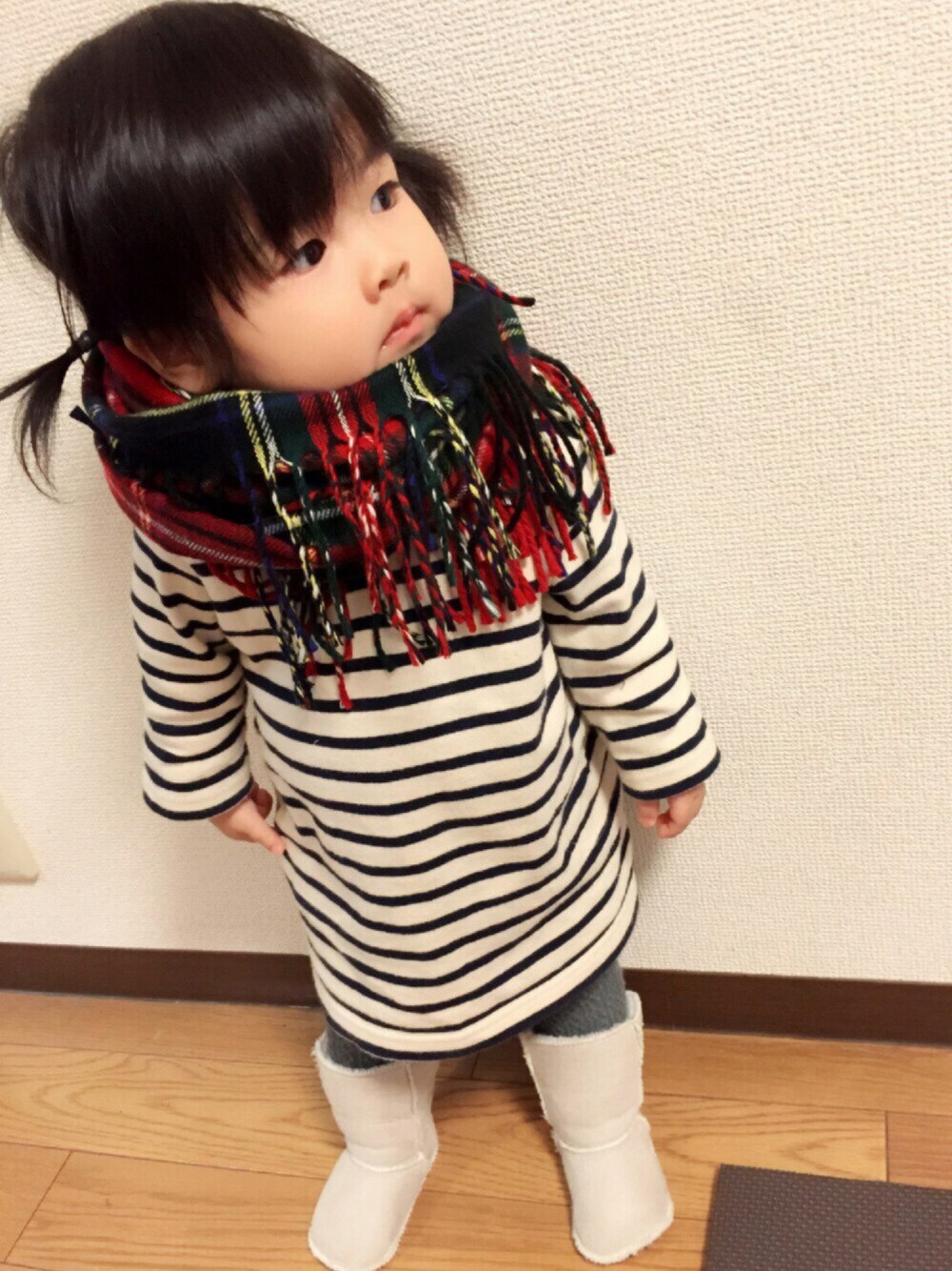 ホワイト系のチュニック、ベージュ系のブーツ、レッド系のマフラーを着用したキッズの冬コーディネートの1枚目の写真