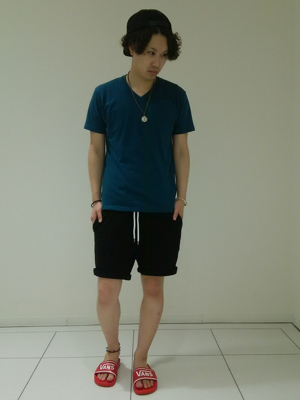 ブラック系のパンツ、グリーン系のトップス、レッド系のシューズを着用したメンズの夏コーディネートの1枚目の写真
