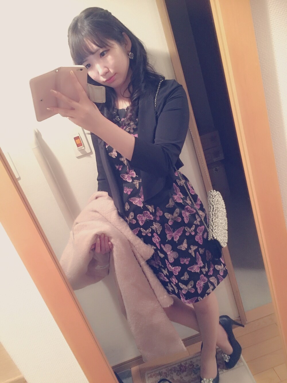 ブラック系のドレス、ピンク系のダウンジャケット/コート、ブラック系のパンプスを着用したレディースの冬コーディネートの1枚目の写真