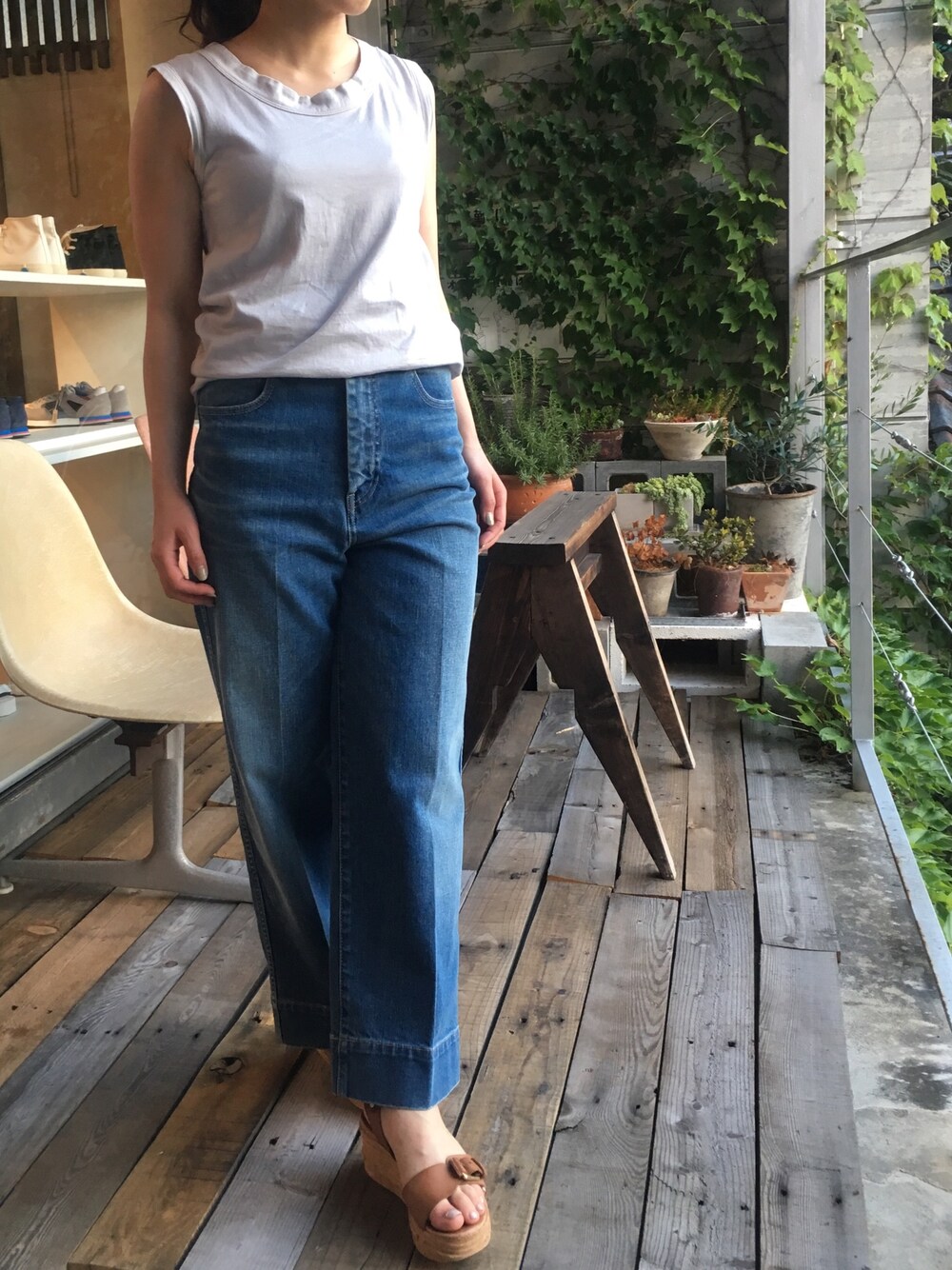 グレー系のトップス、ブルー系のデニムパンツ、ブラウン系のサンダルを着用したレディースの夏コーディネートの1枚目の写真
