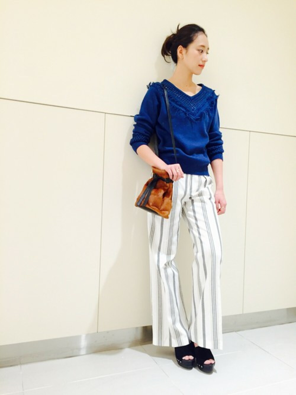 ホワイト系のその他パンツ、イエロー系のバックパック/リュック、ブルー系のニット/セーターを着用したレディースの春コーディネートの1枚目の写真