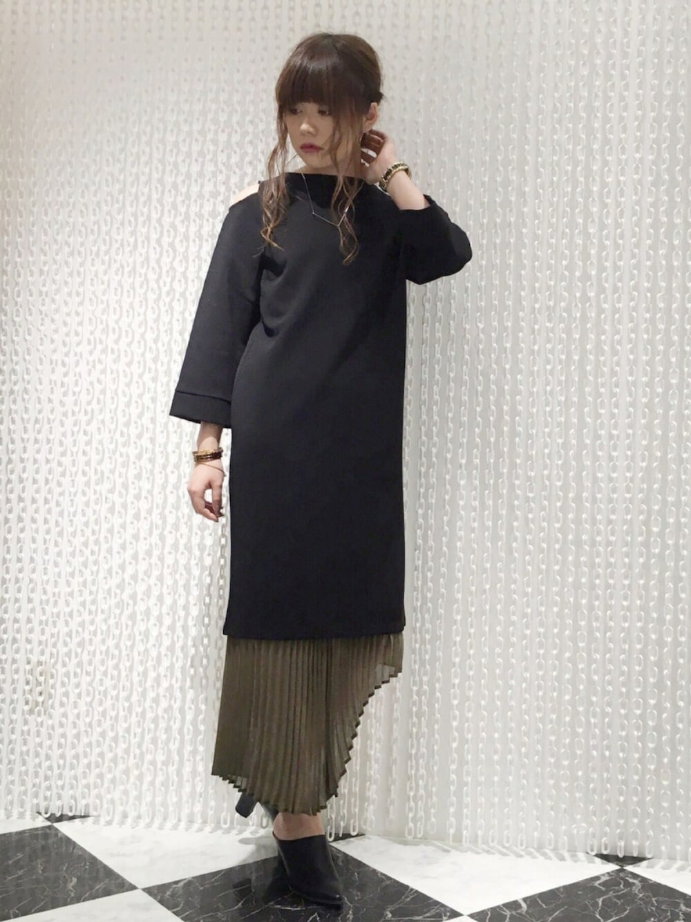 ブラック系のワンピース、グリーン系のスカートを着用したレディースの秋コーディネートの1枚目の写真