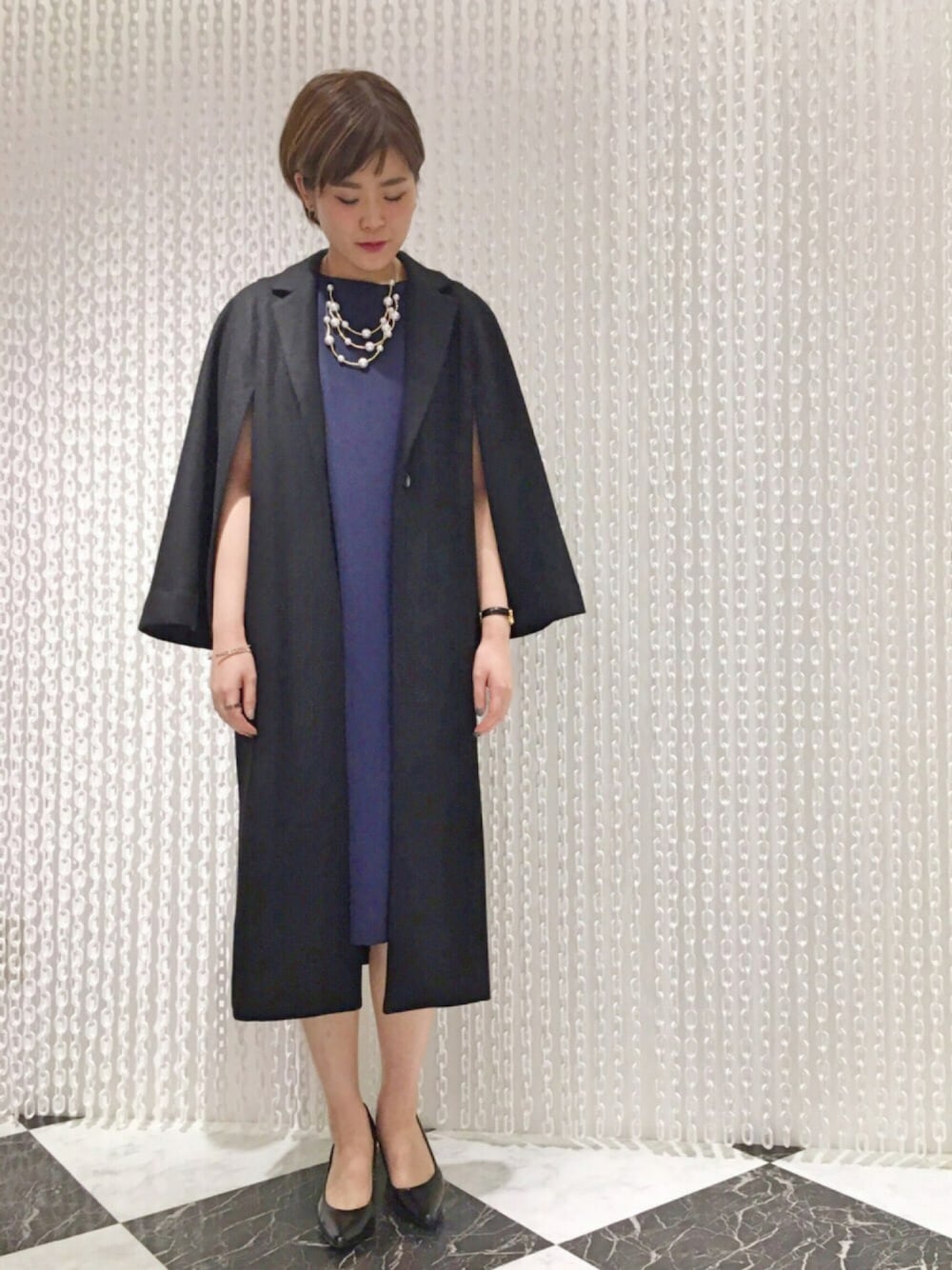 「OSMOSIS、オケージョン、結婚式、結婚式二次会スタイル、スリット、ワンピース、コート、ブラック、ネイビー、パールネックレス」｜「OSMOSISのケープコート（チェスターコート、ブラック系）」を使った、OSMOSIS天王寺ミオ店さん（レディース・163cm）の秋コーディネートの1枚目の写真