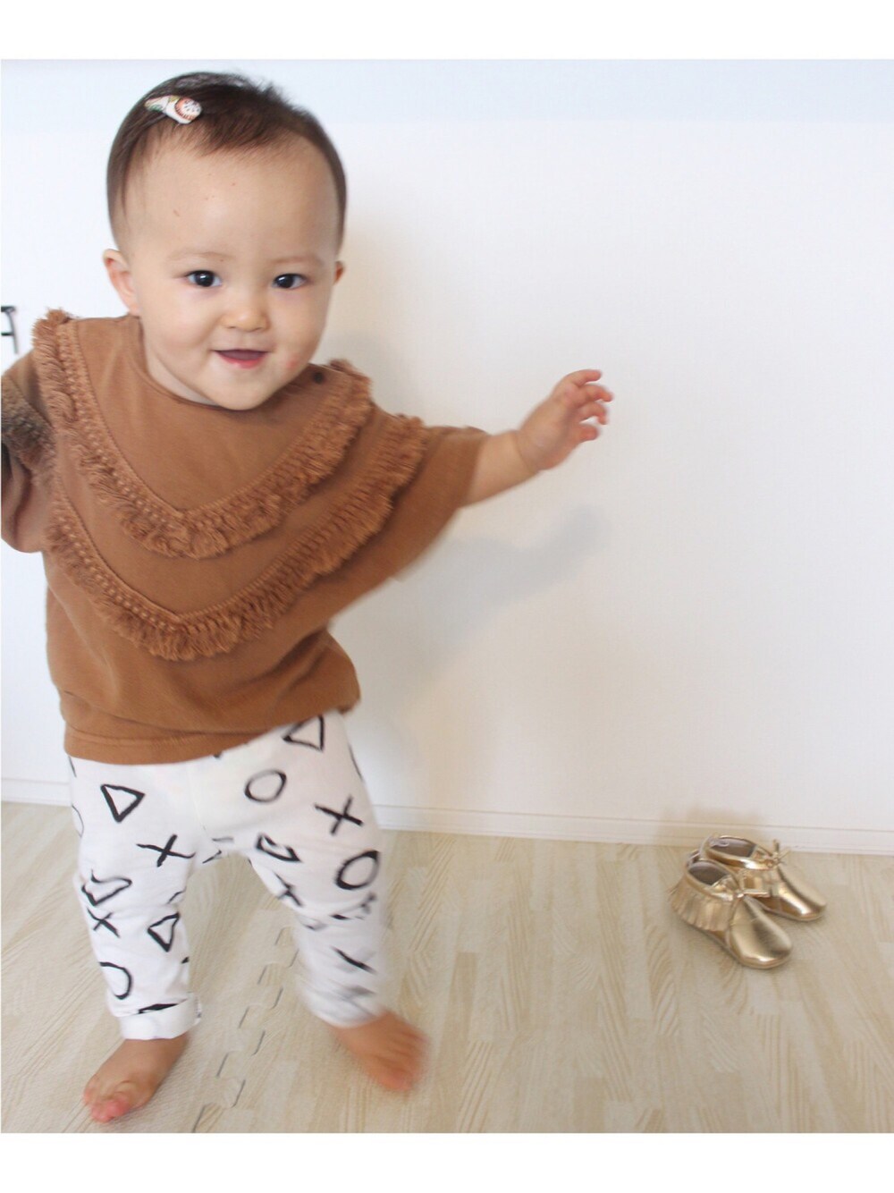 ブラウン系のTシャツ/カットソー、ホワイト系のパンツ、ゴールド系のシューズを着用したキッズの秋コーディネートの1枚目の写真