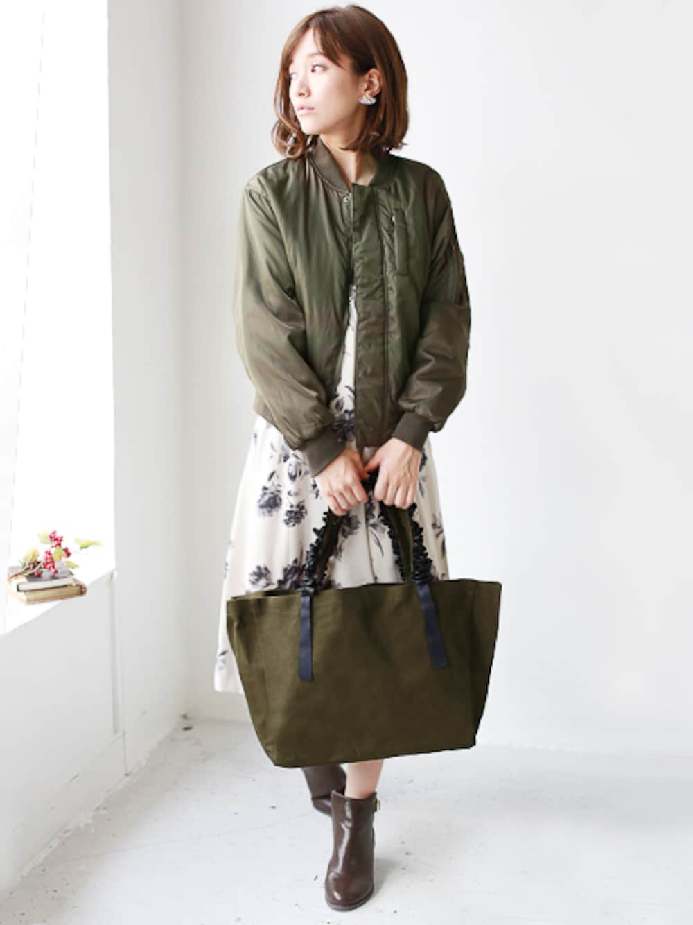 グリーン系のトートバッグ、ブラウン系のブーティを着用したレディースの秋コーディネートの1枚目の写真