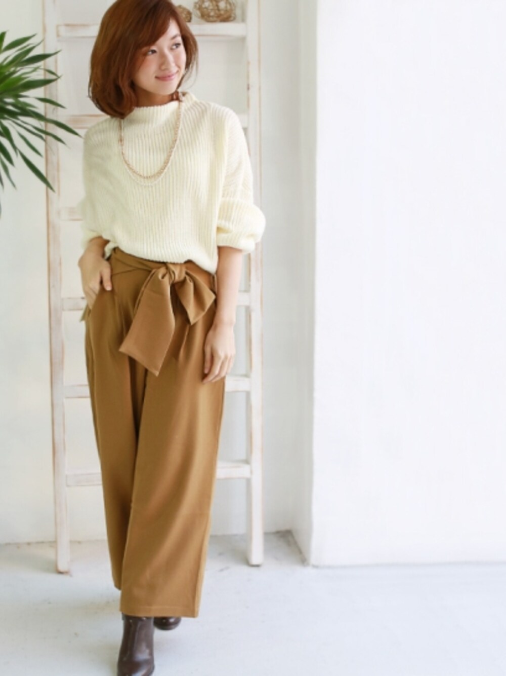 イエロー系のその他パンツ、ホワイト系のニット/セーター、ブラウン系のブーティを着用したレディースの秋コーディネートの1枚目の写真
