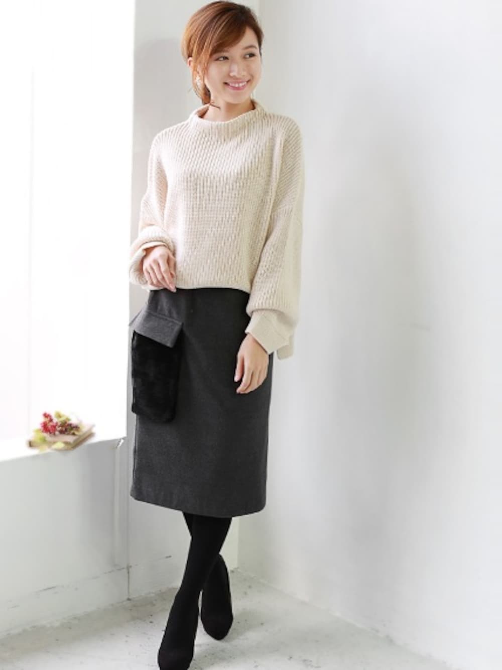 グレー系のスカート、ホワイト系のニット/セーターを着用したレディースの秋コーディネートの1枚目の写真