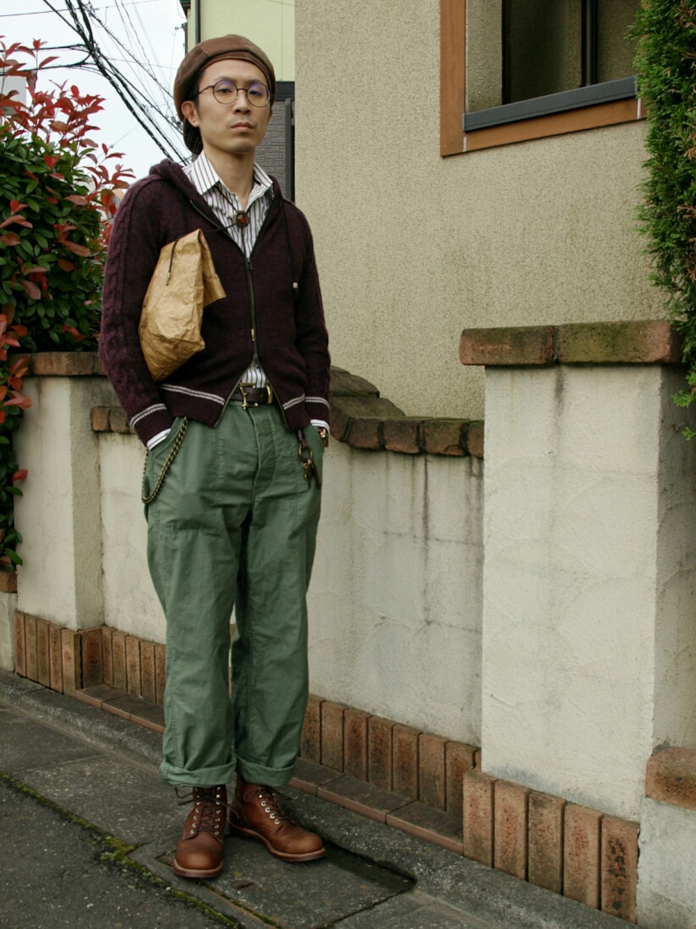 レッド系のパーカー、ブラウン系のブーツ、ブラウン系のクラッチバッグを着用したメンズの夏コーディネートの1枚目の写真