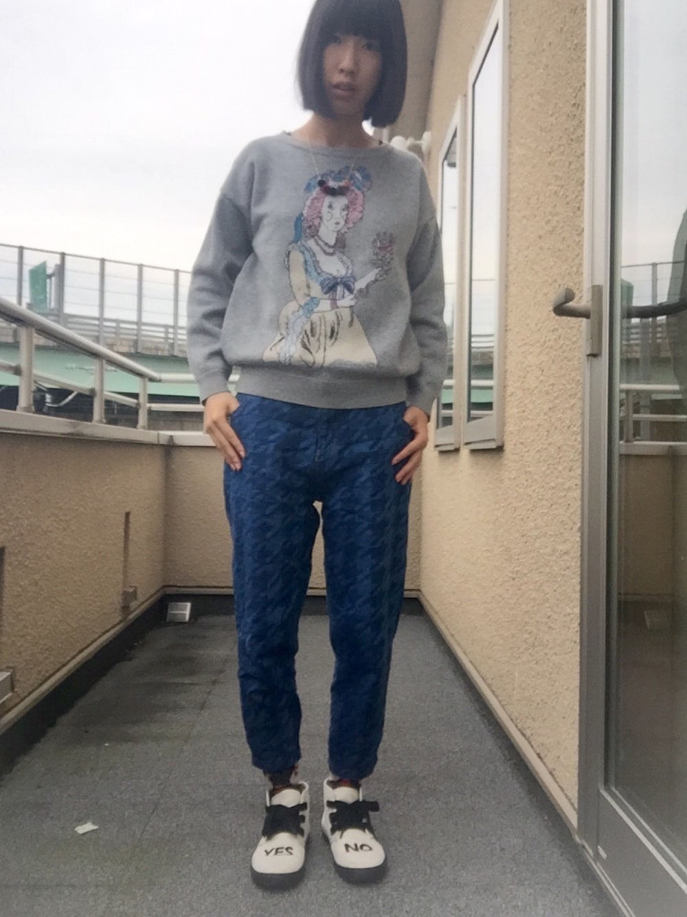 グレー系のニット/セーター、ブルー系のデニムパンツ、ホワイト系のスニーカーを着用したレディースの秋コーディネートの1枚目の写真