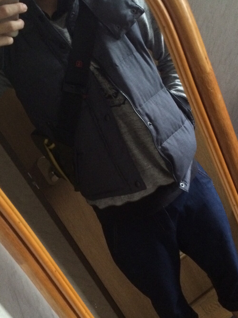 ブルー系のデニムパンツ、グリーン系のメッセンジャーバッグ、グレー系のダウンベストを着用したメンズの秋コーディネートの1枚目の写真