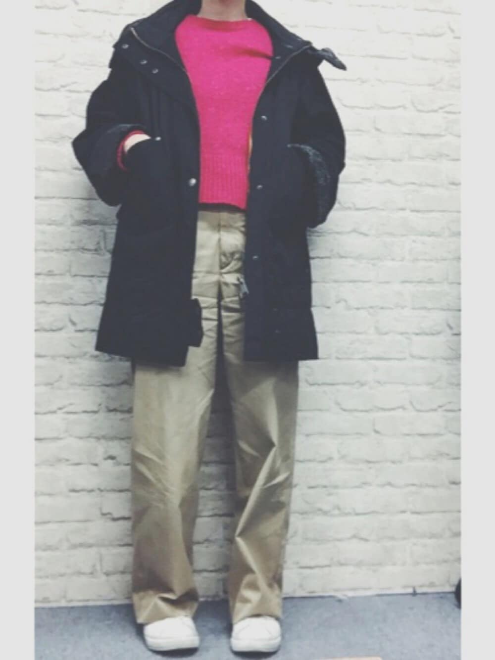 ピンク系のニット/セーター、ブラック系のダウンジャケット/コート、ベージュ系のチノパンツを着用したレディースの冬コーディネートの1枚目の写真