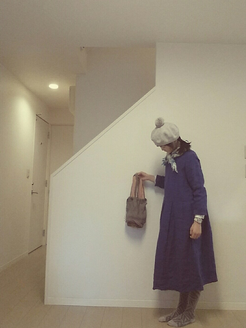 グレー系のかごバッグ、ブルー系のワンピース、ホワイト系の腕時計を着用したレディースの冬コーディネートの1枚目の写真