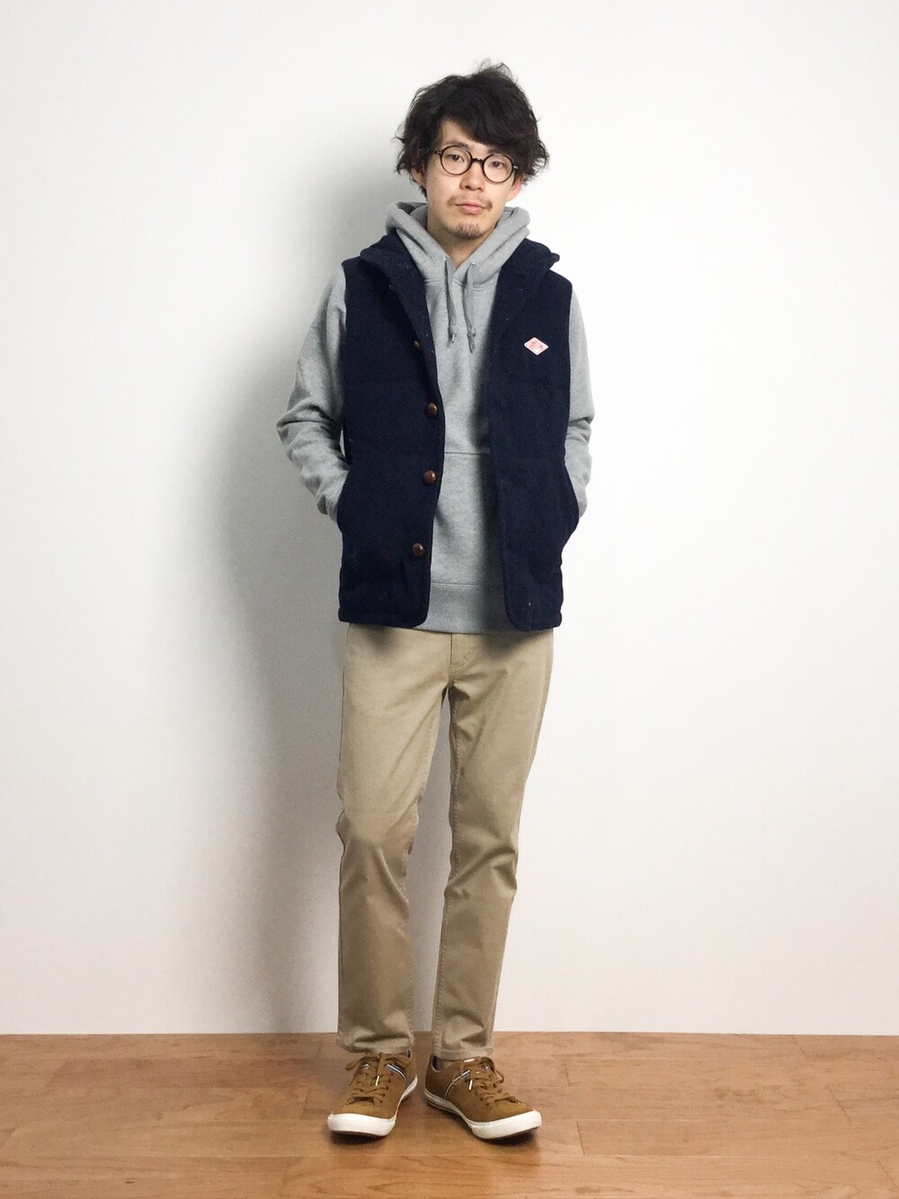 イエロー系のスニーカー、ブルー系のダウンベスト、ベージュ系のその他パンツを着用したメンズの秋コーディネートの1枚目の写真