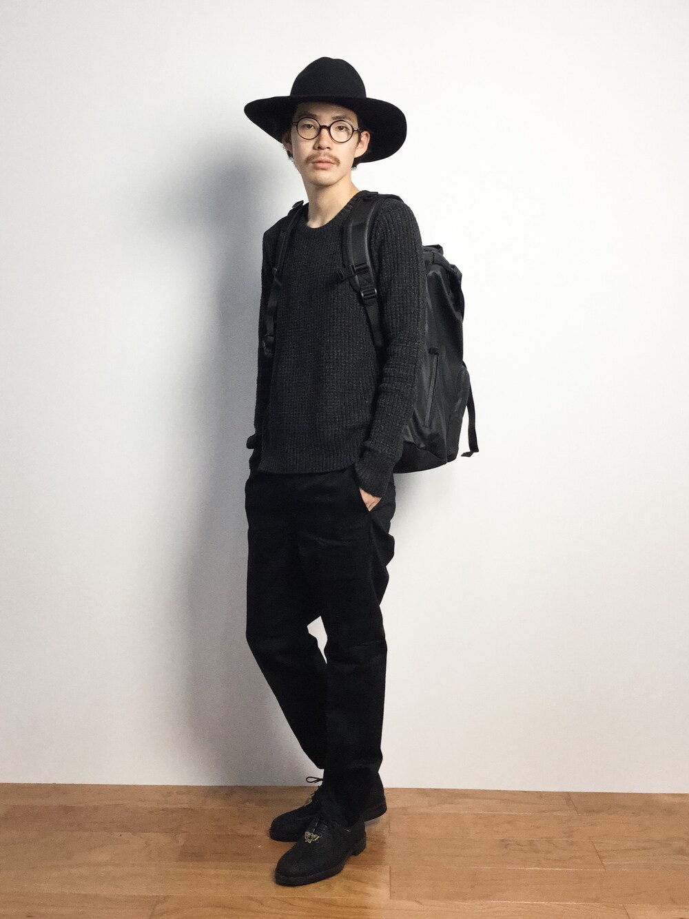 「オールブラック、黒リュック、黒パンツ、黒ニット、ツバ広ハット、黒ハット」｜「NUMBER (N)INE DENIMの【NUMBER (N)INE×LOVELESS・GUILD PRIME】COLLABORATION BACK PACK（バックパック/リュック、ブラック系）」を使った、ナカニシアキラさん（メンズ・172cm）の秋コーディネートの1枚目の写真