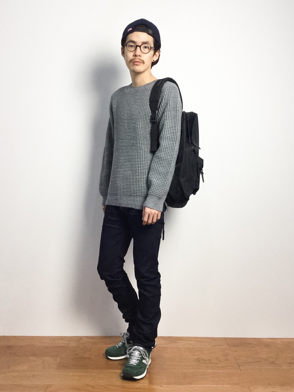 「ニューバランス、黒リュック、グレーニット、キャップ後ろかぶり、キャップ×メガネ、グレーのニット」｜「CHUMSの6 Panel B.B. Cap（キャップ、ブルー系）」を使った、ナカニシアキラさん（メンズ・172cm）の秋コーディネートの1枚目の写真