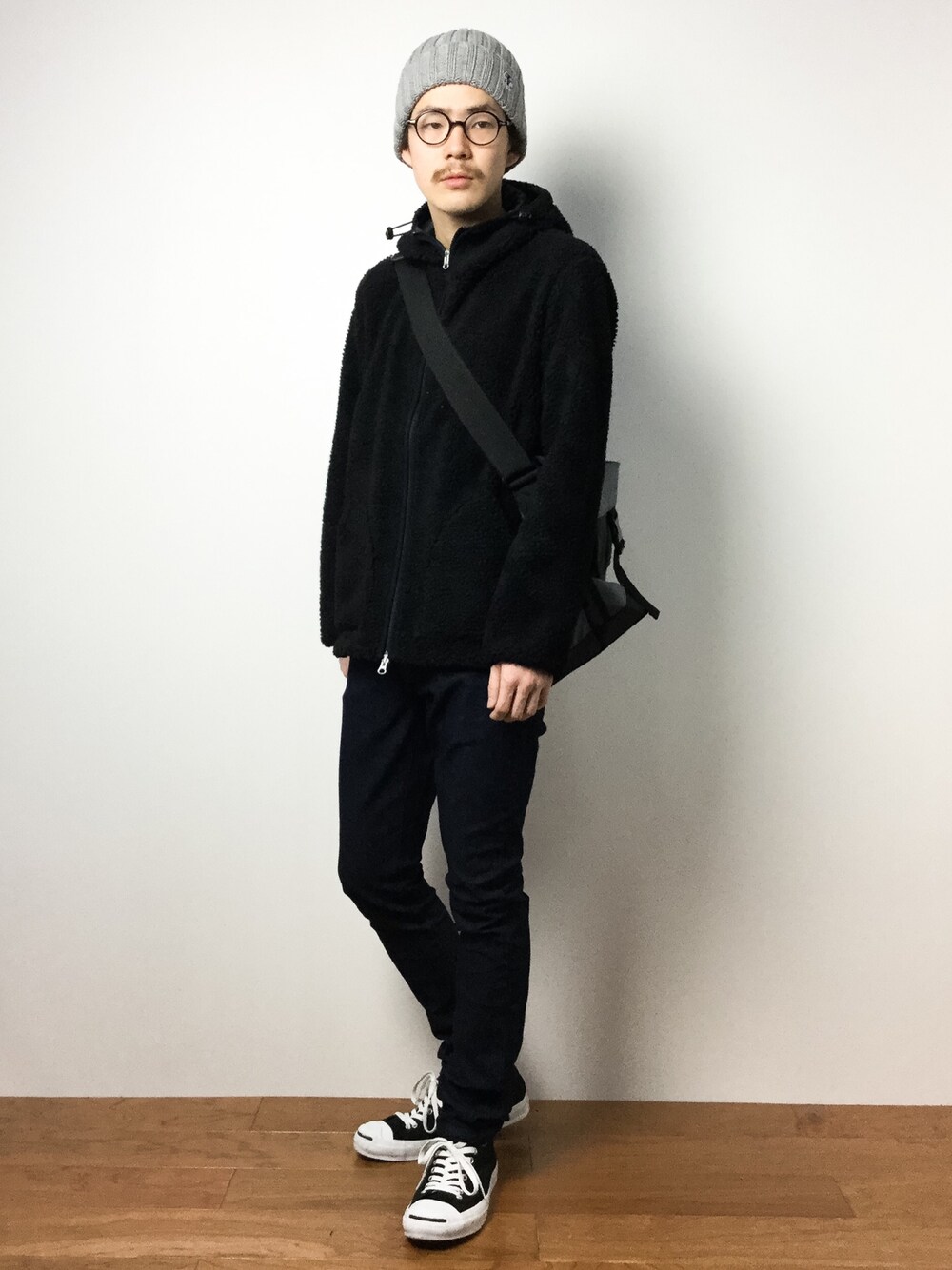 ブラック系のパーカー、グレー系のメッセンジャーバッグ、ブルー系のデニムパンツを着用したメンズの冬コーディネートの1枚目の写真