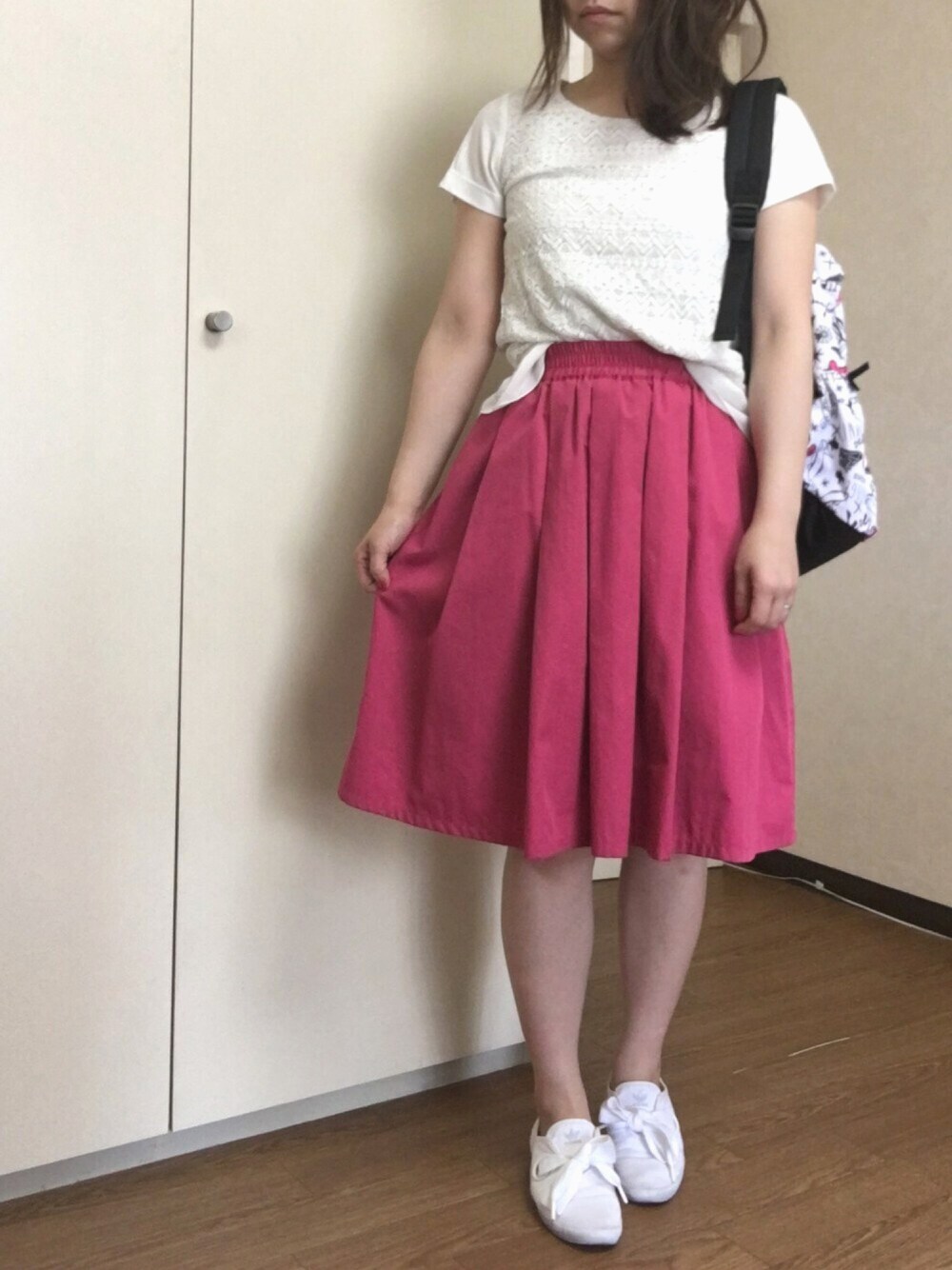 ピンク系のスカート、ホワイト系のスニーカー、ホワイト系のTシャツ/カットソーを着用したレディースの春コーディネートの1枚目の写真