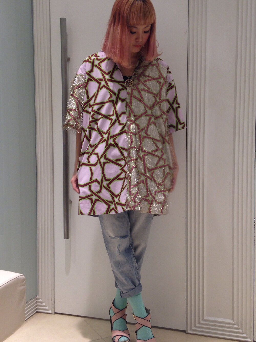 ピンク系のチュニック、ブルー系のデニムパンツ、ピンク系のサンダルを着用したレディースの春コーディネートの1枚目の写真