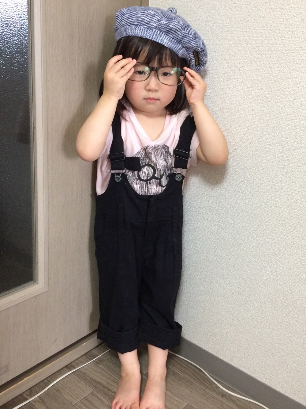 ピンク系のTシャツ/カットソー、ブラック系のサロペット/オーバーオール、ブルー系のハンチング/ベレー帽を着用したキッズの夏コーディネートの1枚目の写真