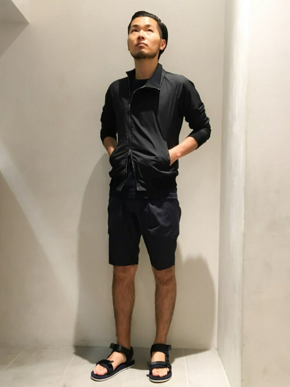 ブラック系のナイロンジャケット、ブルー系のTシャツ/カットソー、ブルー系のカーゴパンツを着用したメンズの夏コーディネートの1枚目の写真