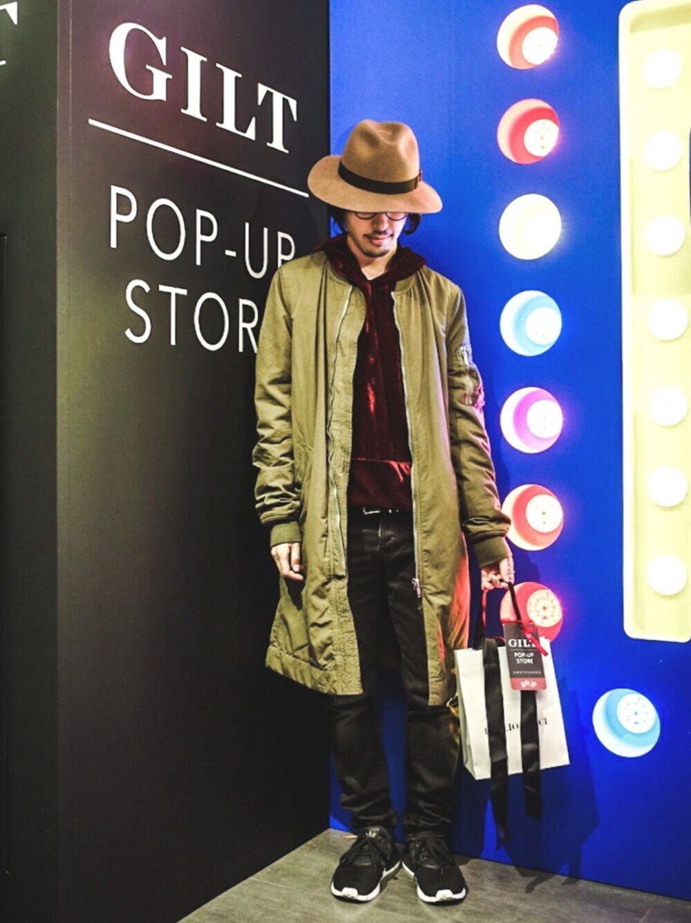 レッド系のパーカー、グリーン系のジャケット/アウター、ブラック系のデニムパンツを着用したメンズの冬コーディネートの1枚目の写真