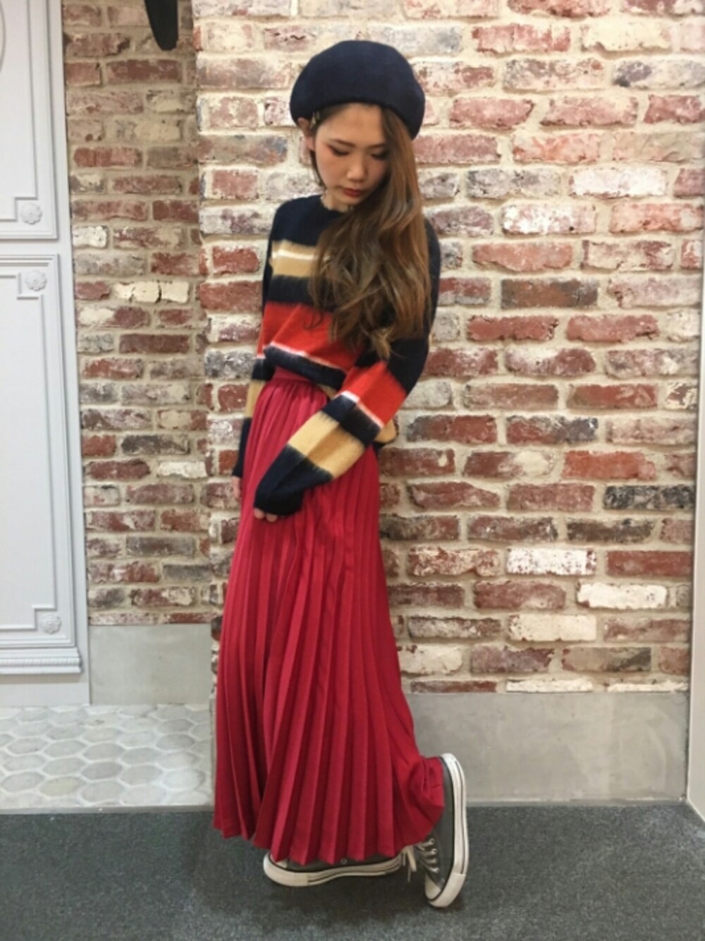 レッド系のスカート、グレー系のスニーカー、ブラック系のニット/セーターを着用したレディースの冬コーディネートの1枚目の写真