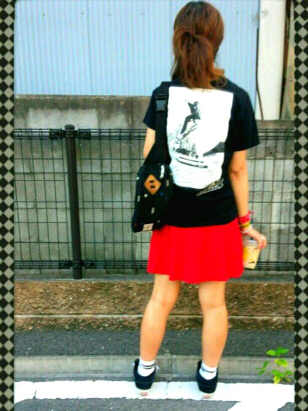 レッド系のスカート、ブラック系のTシャツ/カットソー、ブラック系のスニーカーを着用したレディースの夏コーディネートの1枚目の写真