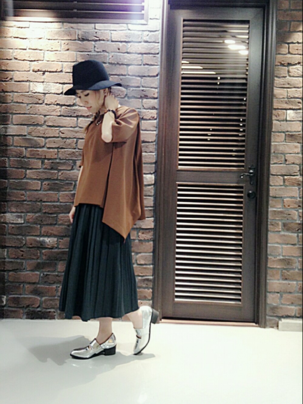 ブラウン系のトップス、グリーン系のスカート、シルバー系のシューズを着用したレディースの秋コーディネートの1枚目の写真