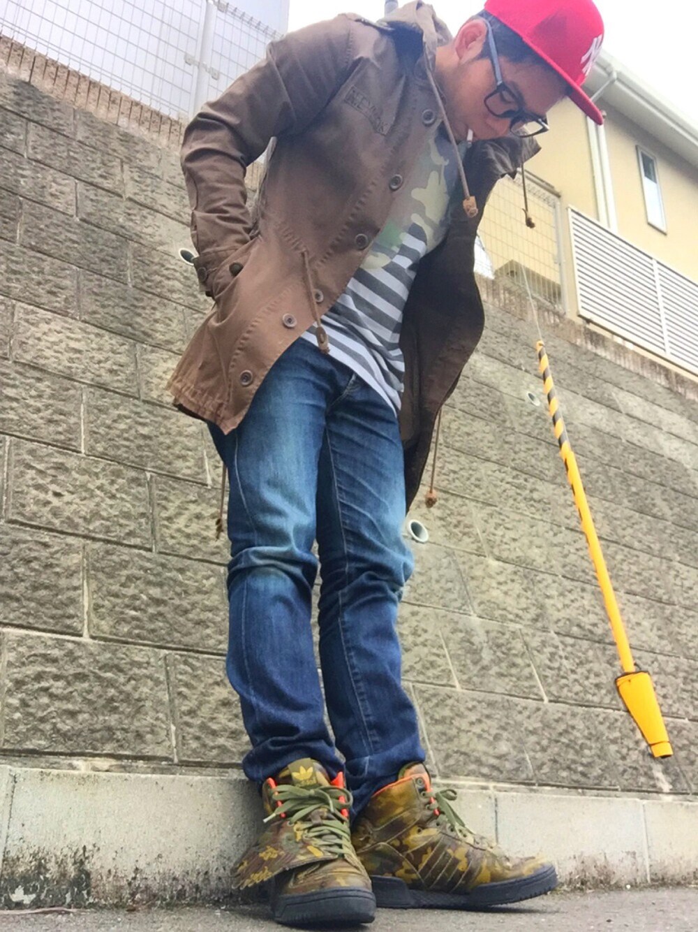 ブラウン系のモッズコート、ブルー系のデニムパンツ、その他のスニーカーを着用したメンズの秋コーディネートの1枚目の写真