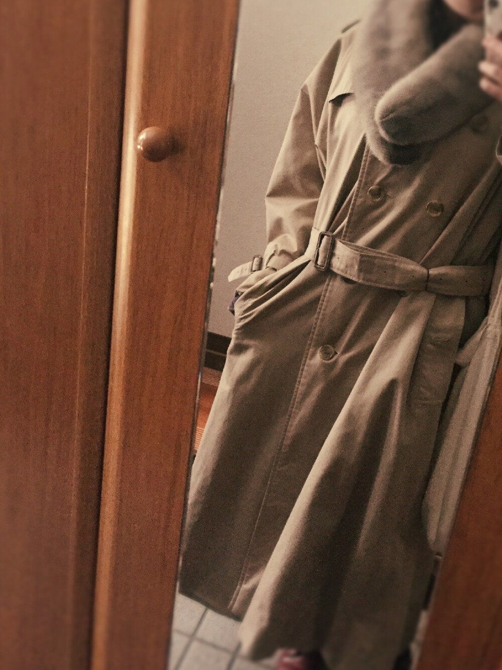 ベージュ系のトレンチコートを着用したレディースの冬コーディネートの1枚目の写真