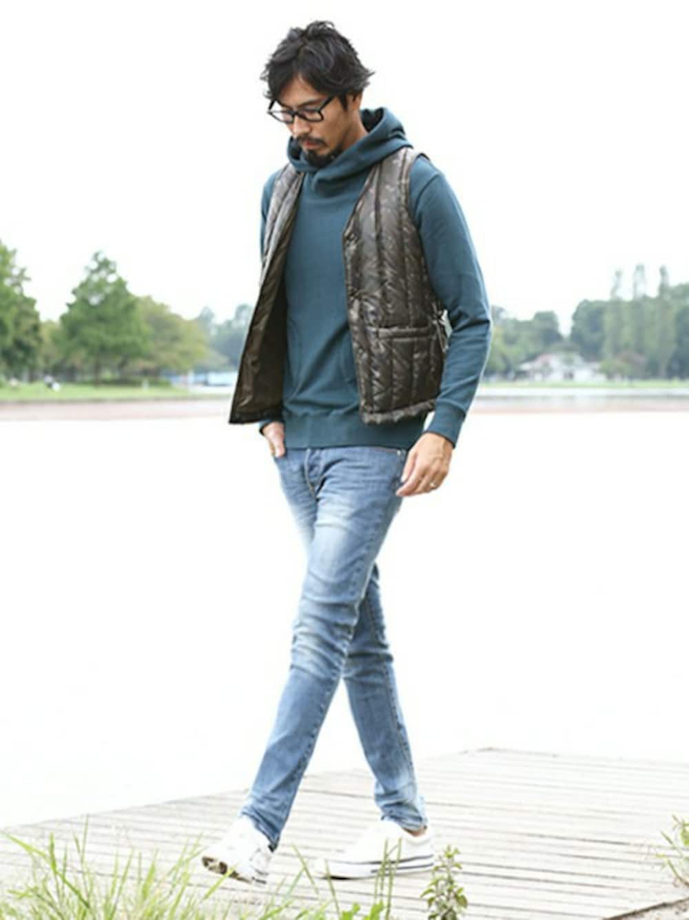 グリーン系のパーカー、グリーン系のダウンベスト、ブルー系のデニムパンツを着用したメンズの秋コーディネートの1枚目の写真