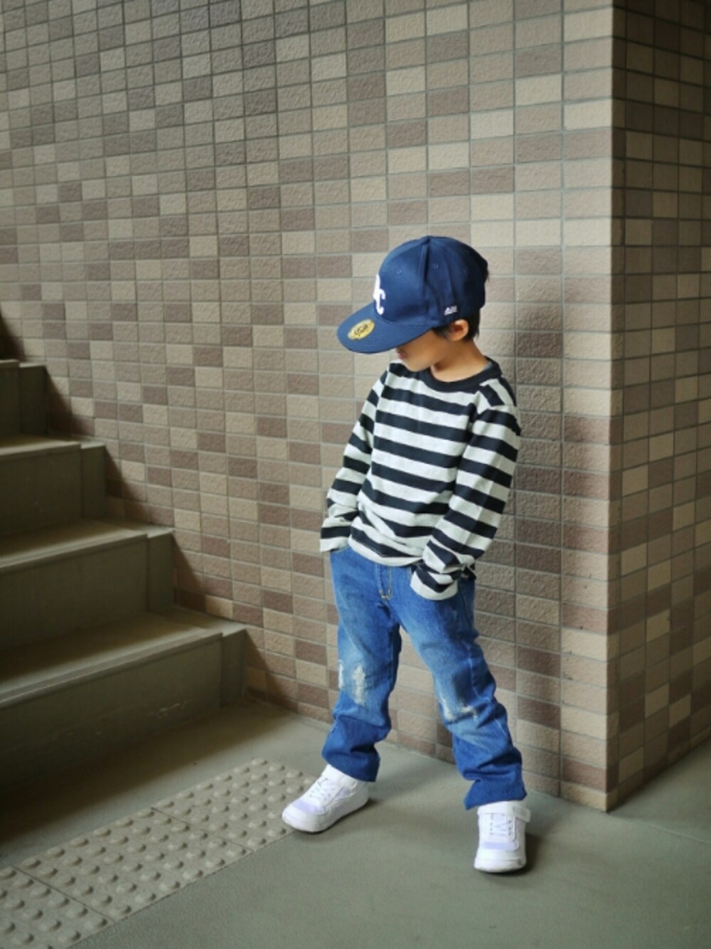 ブルー系のデニムパンツ、ブラック系のTシャツ/カットソー、ホワイト系のスニーカーを着用したキッズの秋コーディネートの1枚目の写真